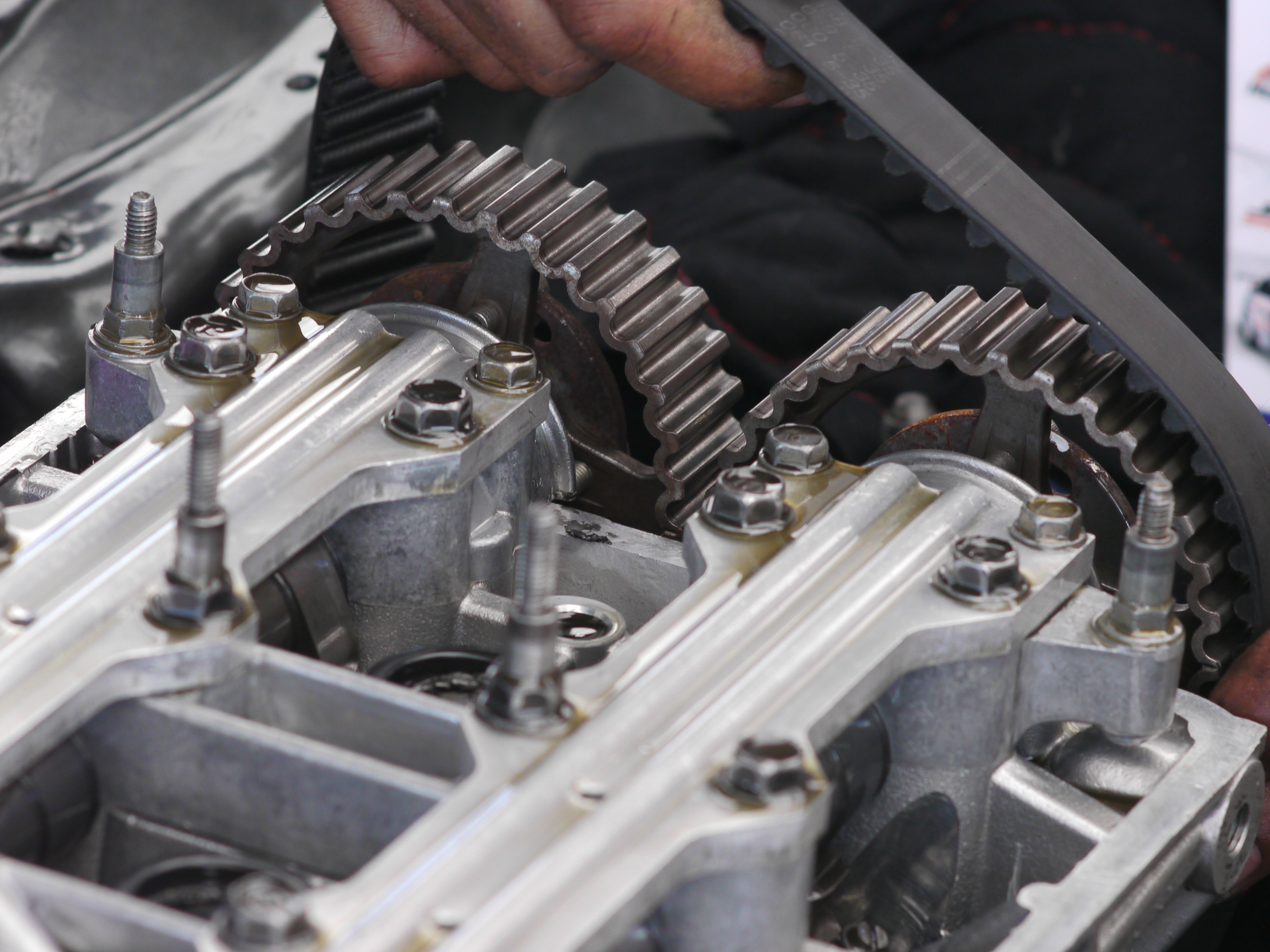 Camshaft timing belt being replaced on car engine with double overhead cams, DOHC. Shallow depth of field with the sprockets in focus.